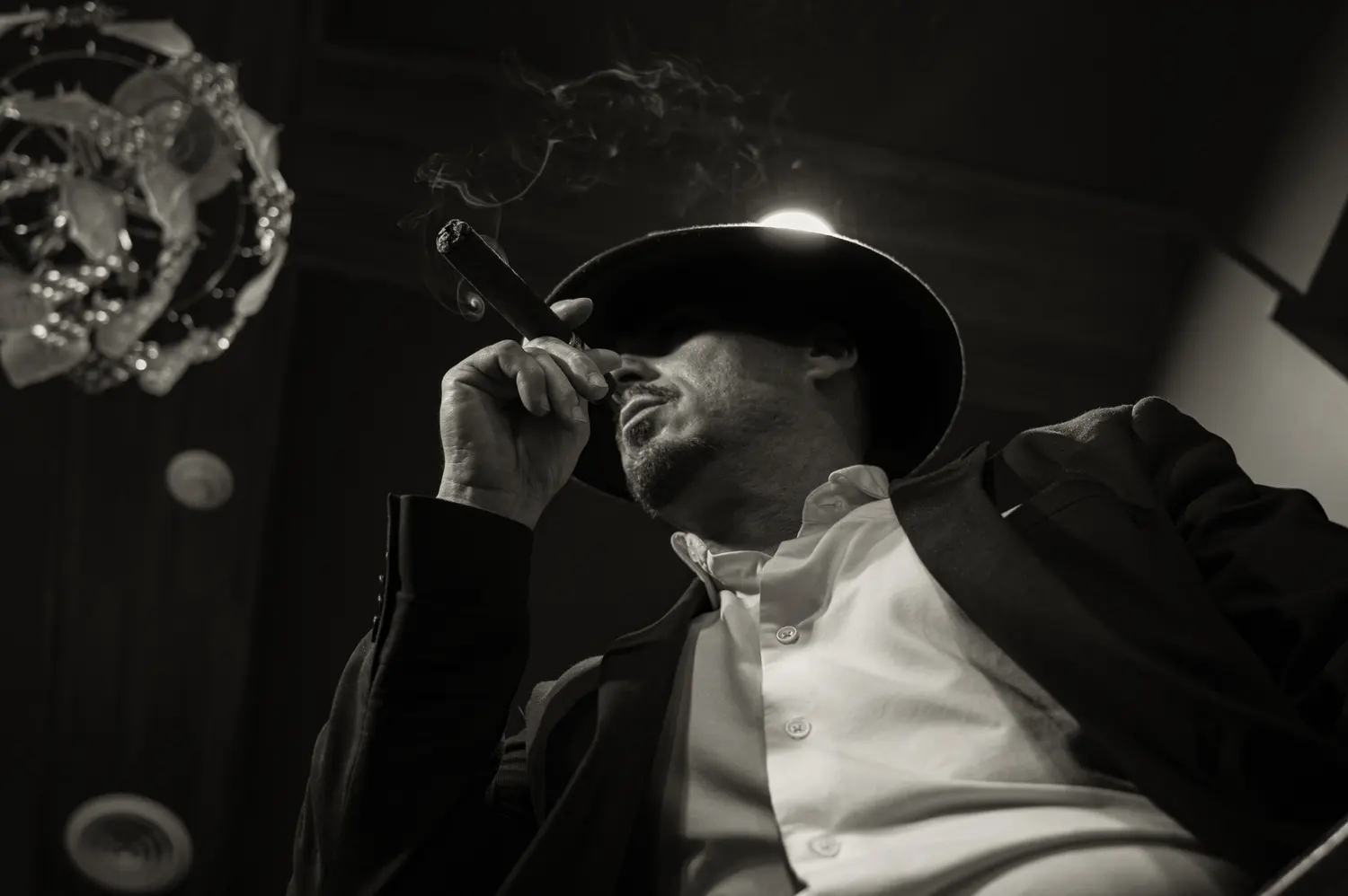 Black and white portrait of a man in a hat smoking a cigar