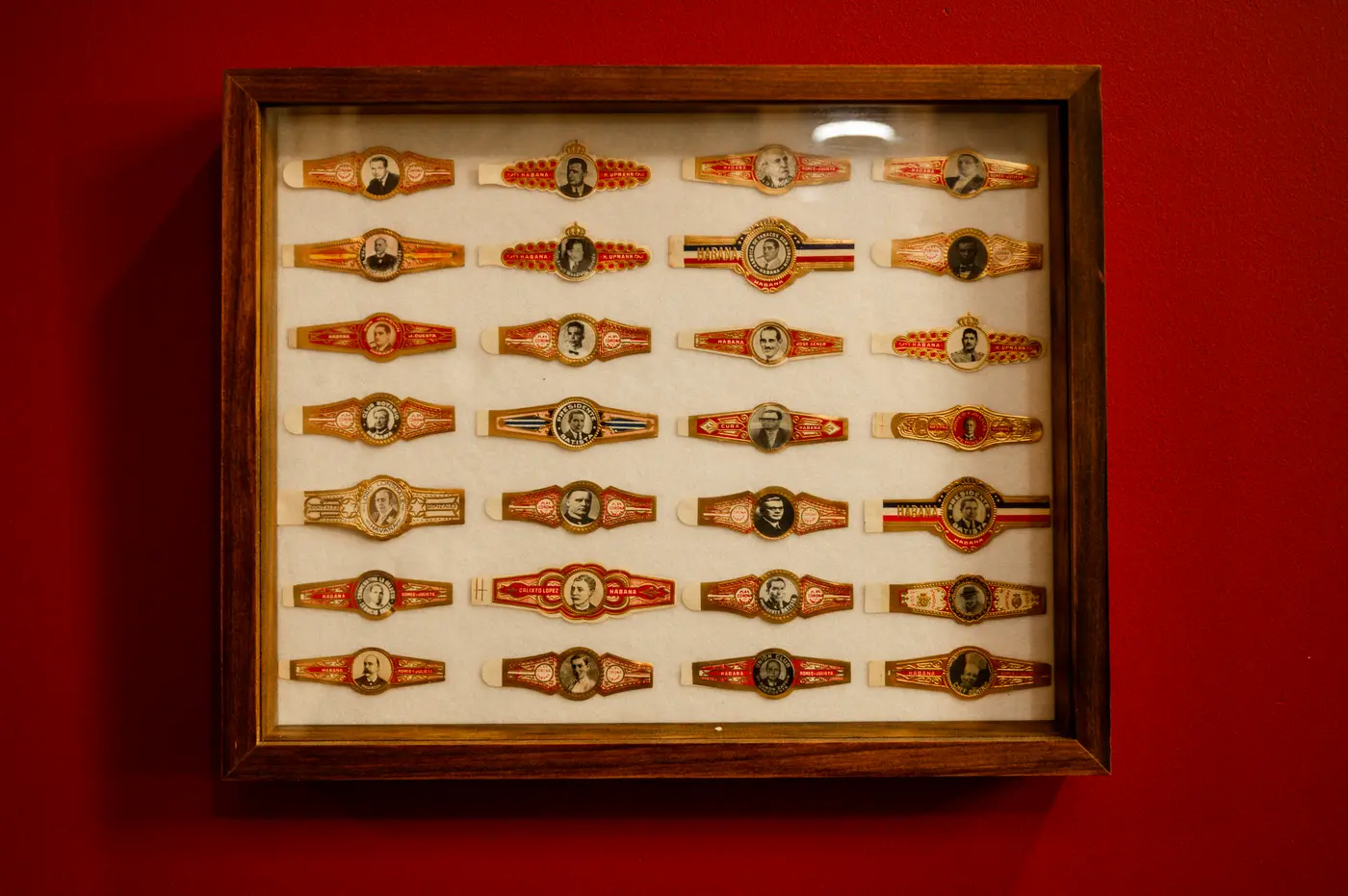A frame of vintage cigar bands on a red wall