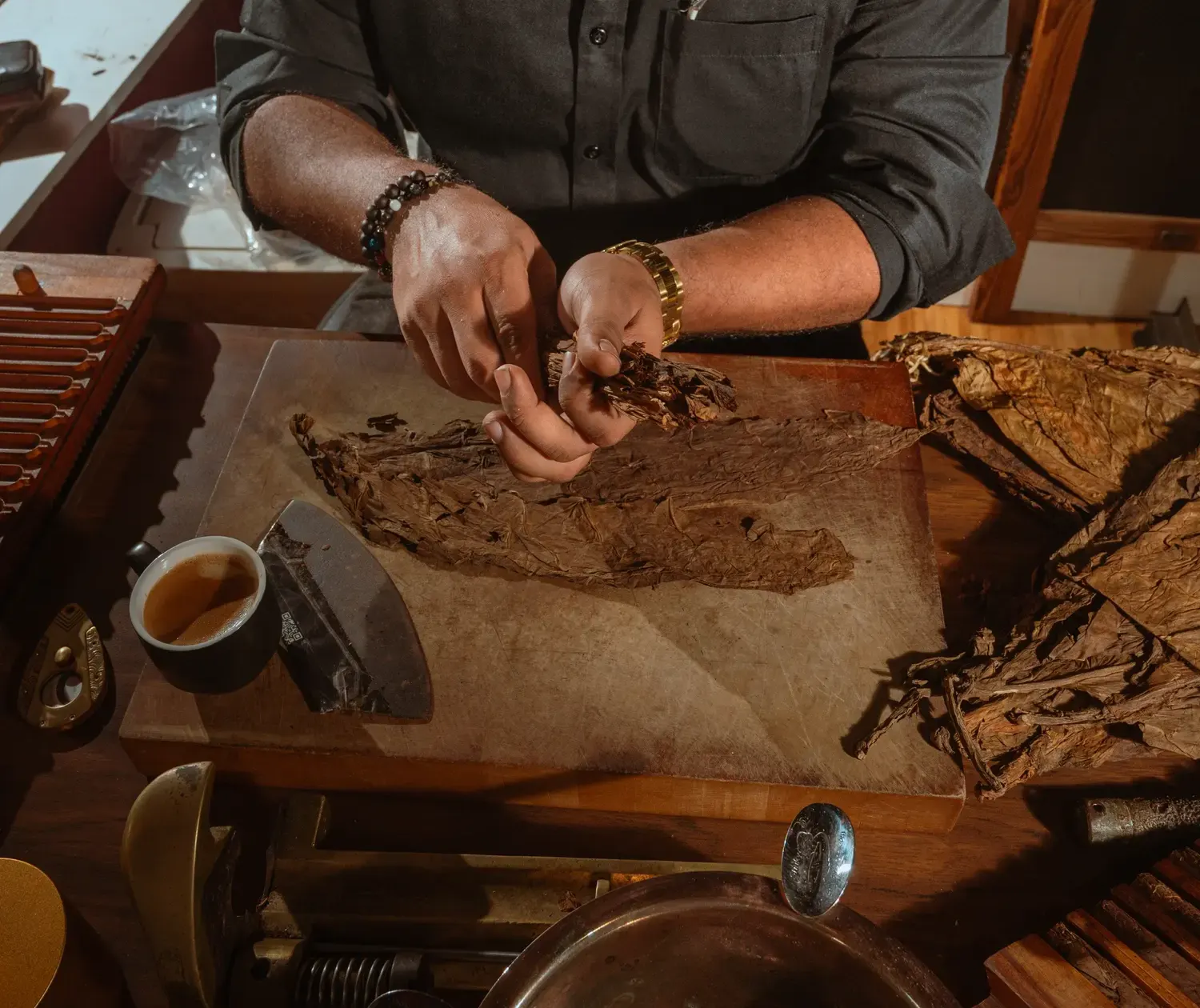 Manos trabajando una hoja de tabaco sobre la tabla de torcido