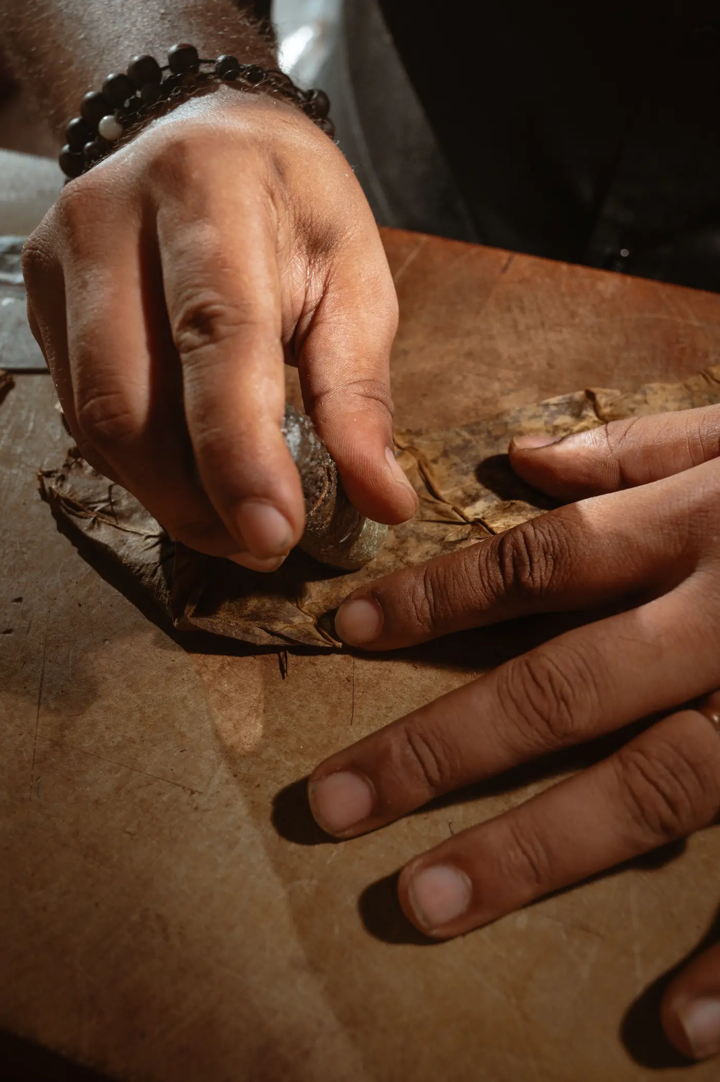 Hands rolling a cigar on a tobacco leaf