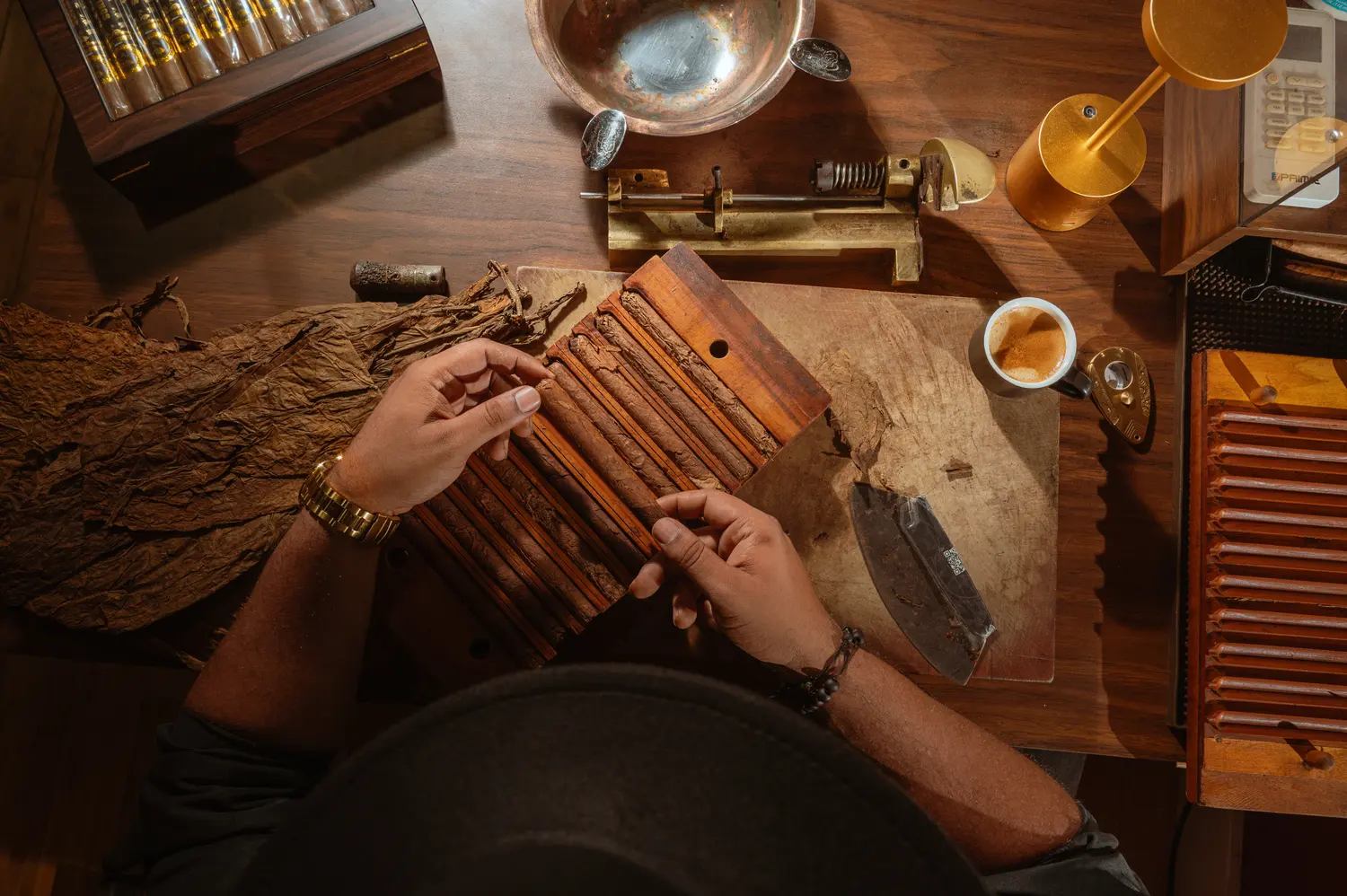Hands arranging hand-rolled cigars in a wooden mold